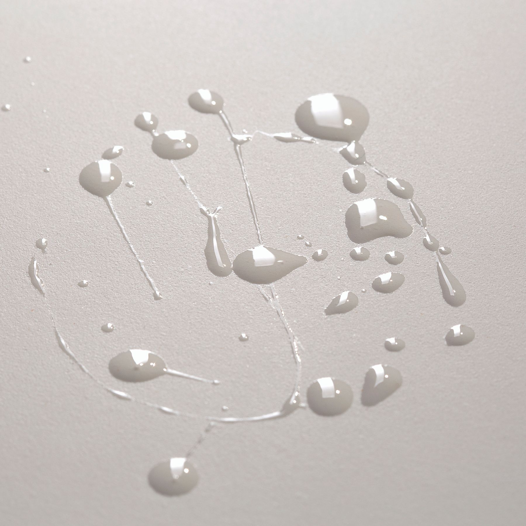 Gouttes d'un liquide clair sur fond neutre.