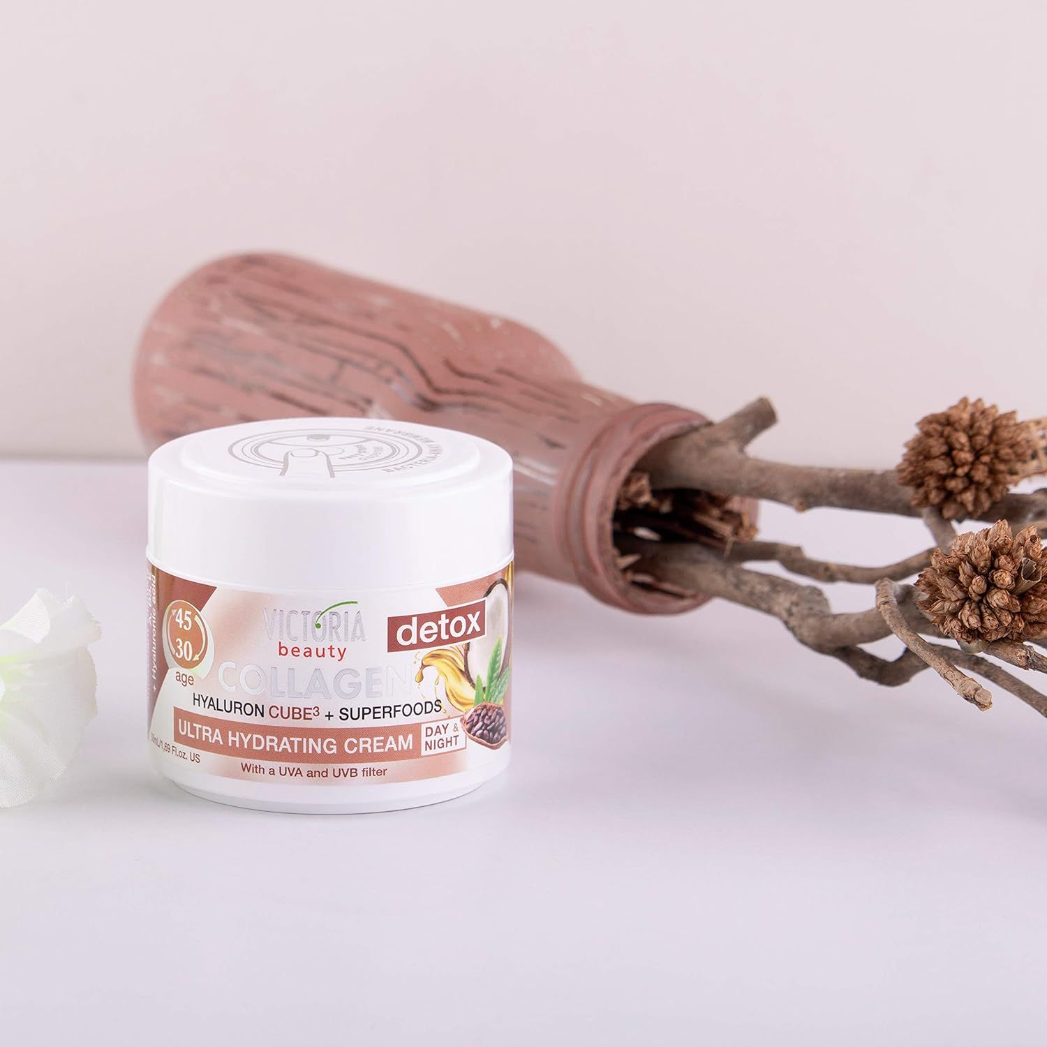 Victoria Beauty Collageencrème pot naast een vaas met takken.