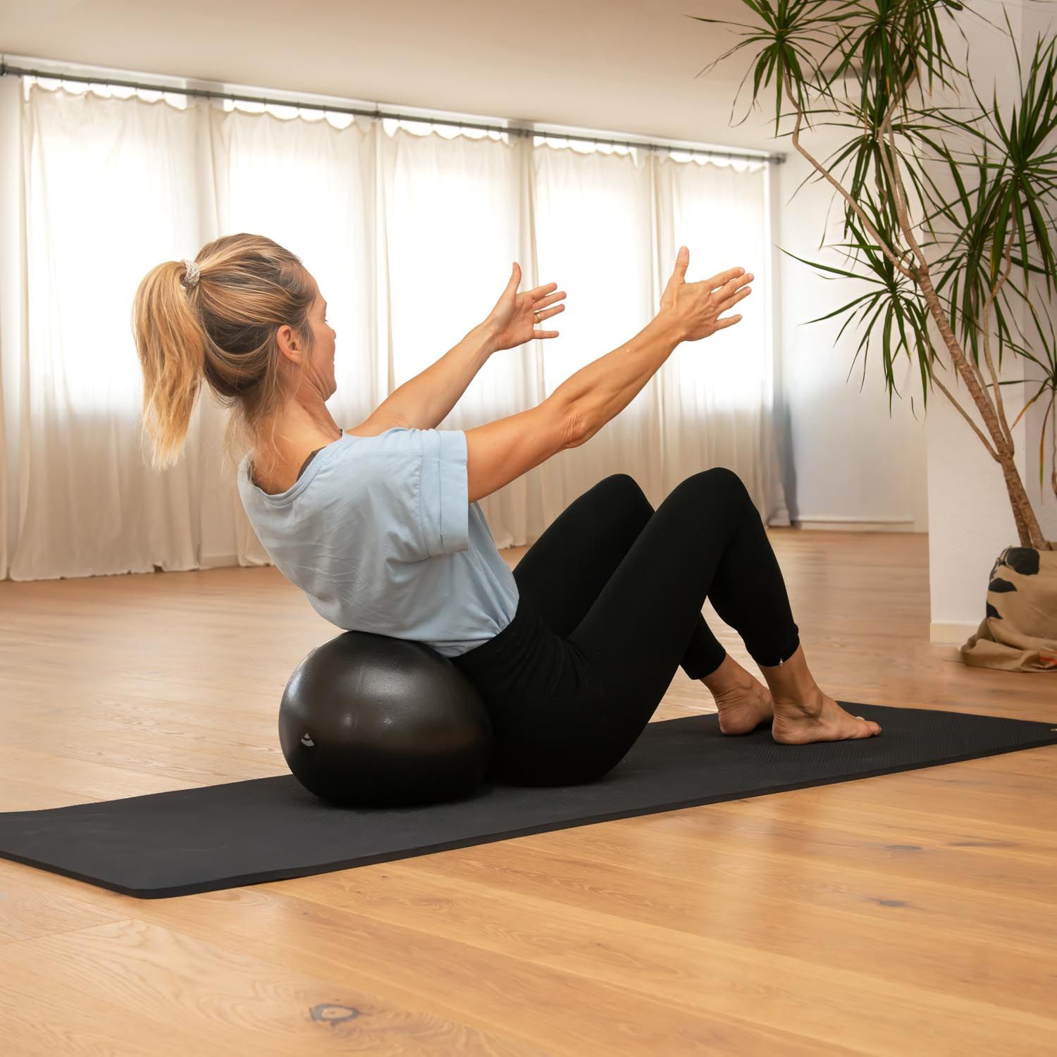 Vrouw doet Pilates zittend op een bal.