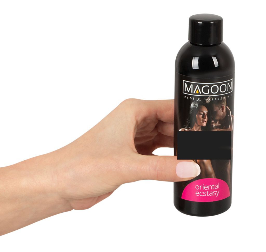 Hand houdt zwarte fles Magoon erotische massageolie Oriental Ecstasy, afbeelding deels geblokkeerd.