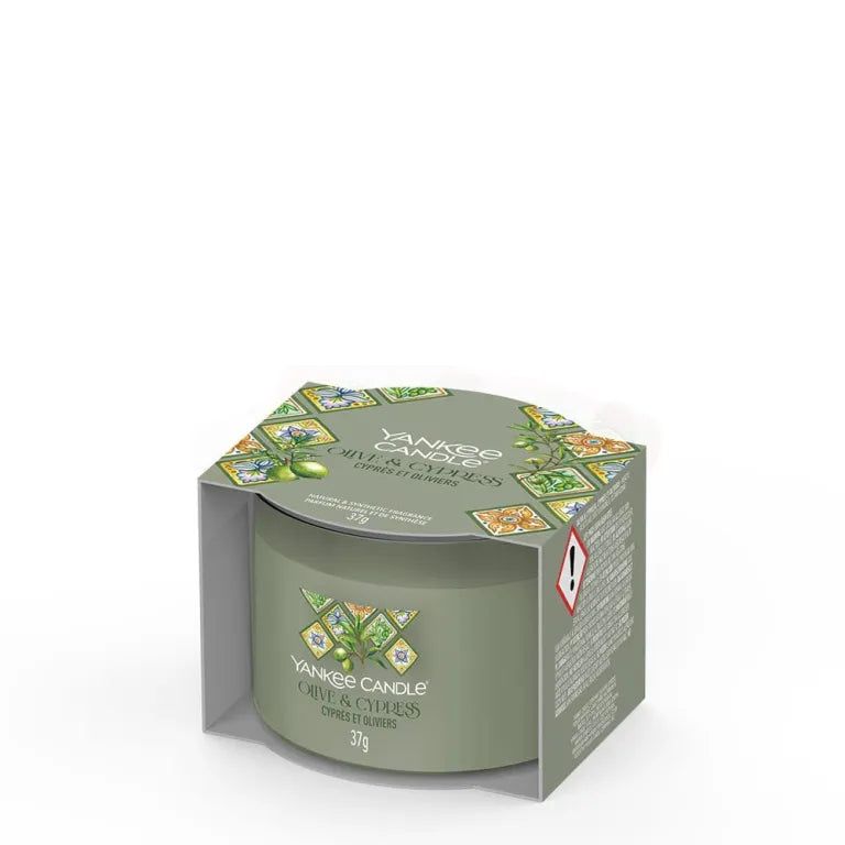 Bougie verte dans emballage. Inscription: Yankee Candle, Olive & Cypress, 37g. Emballage avec motif Olive & Cyprès.