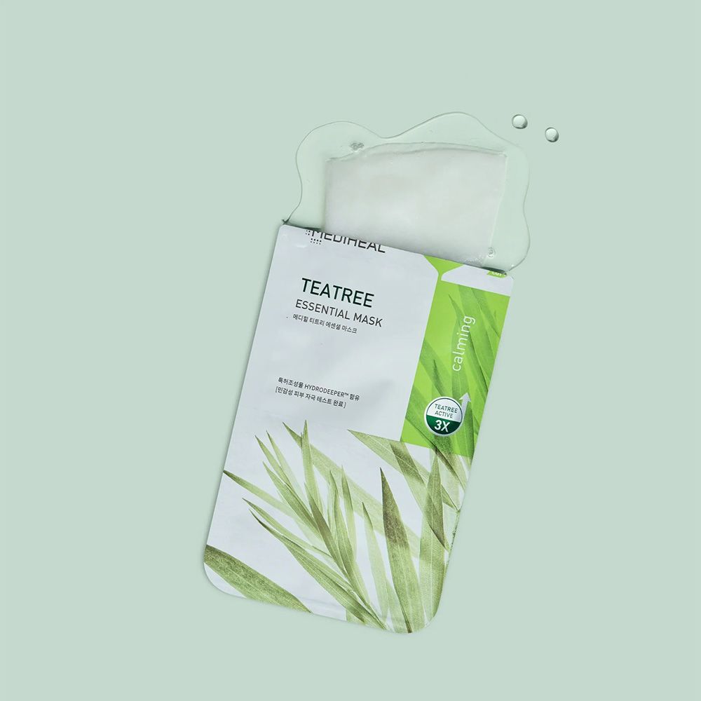 Emballage ouvert avec masque. Inscription: Tea Tree Essential Mask. Bande verte avec texte. Eau et gouttes.