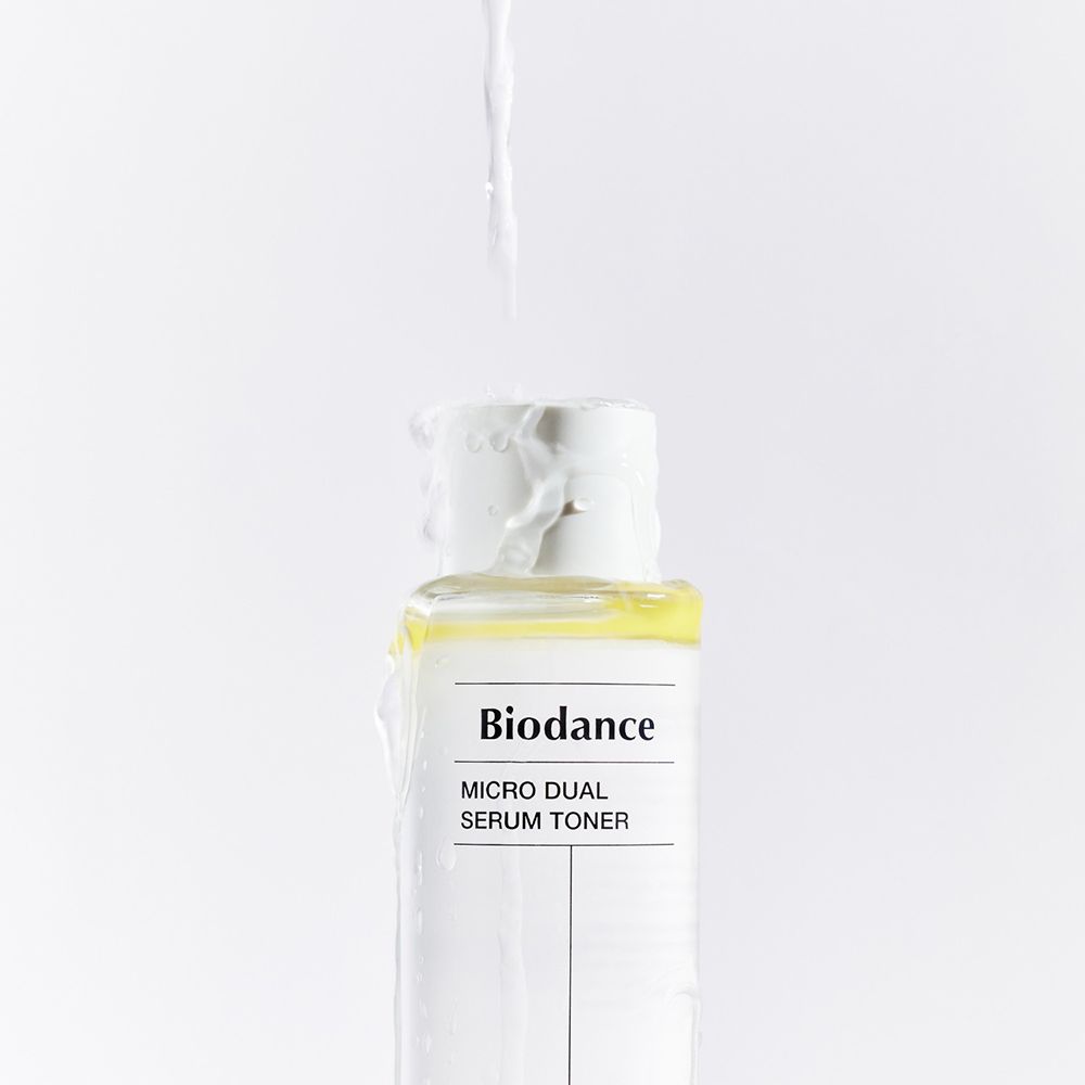 Transparante fles, opschrift: BIODANCE Micro Dual Serum Toner. Vloeistof stroomt uit de opening.