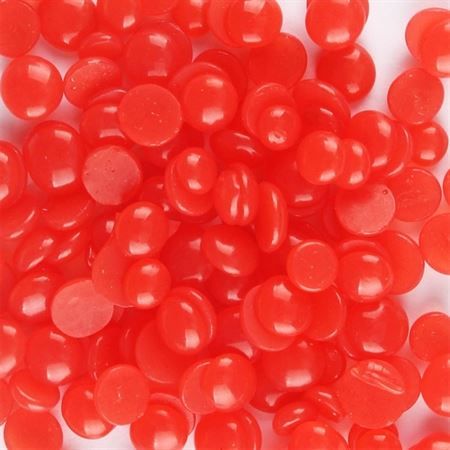 Gros plan sur de nombreuses petites perles de cire rouges parfumées à la fraise.