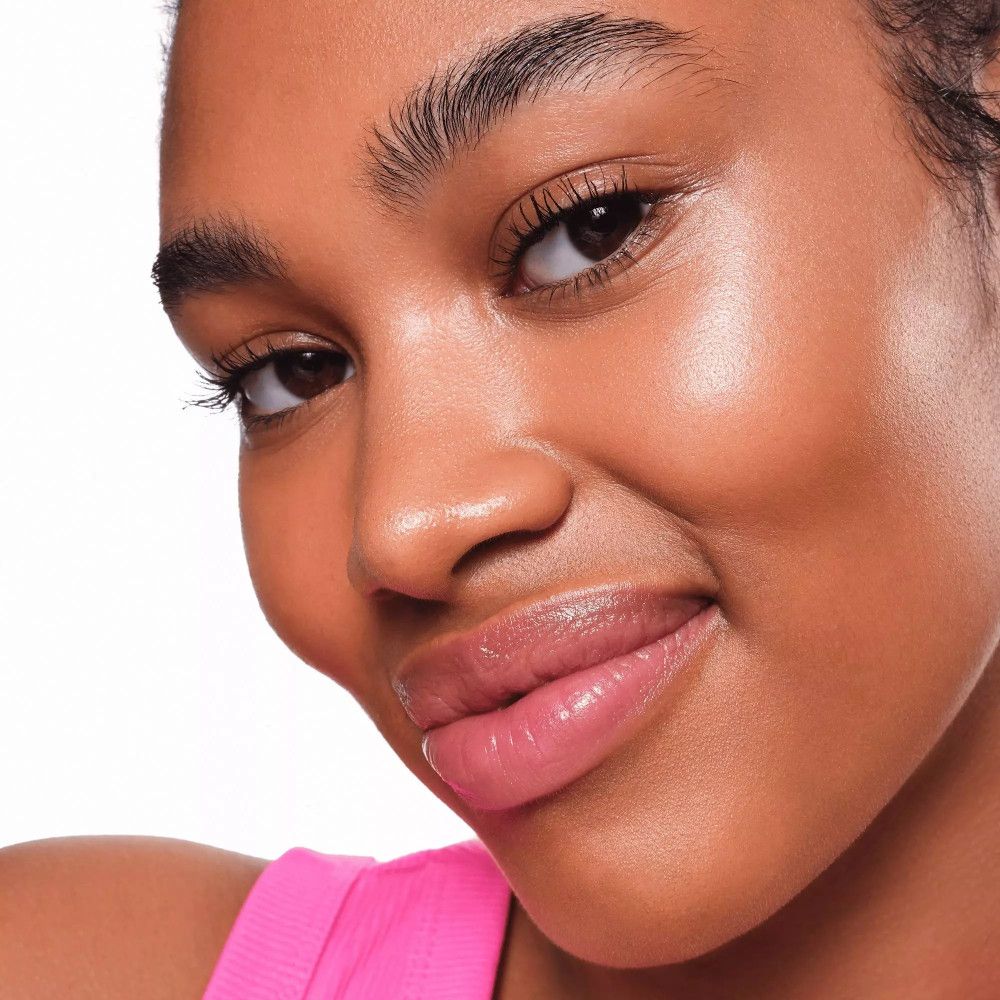 Portrait d'une femme avec peau illuminée. Haut rose.