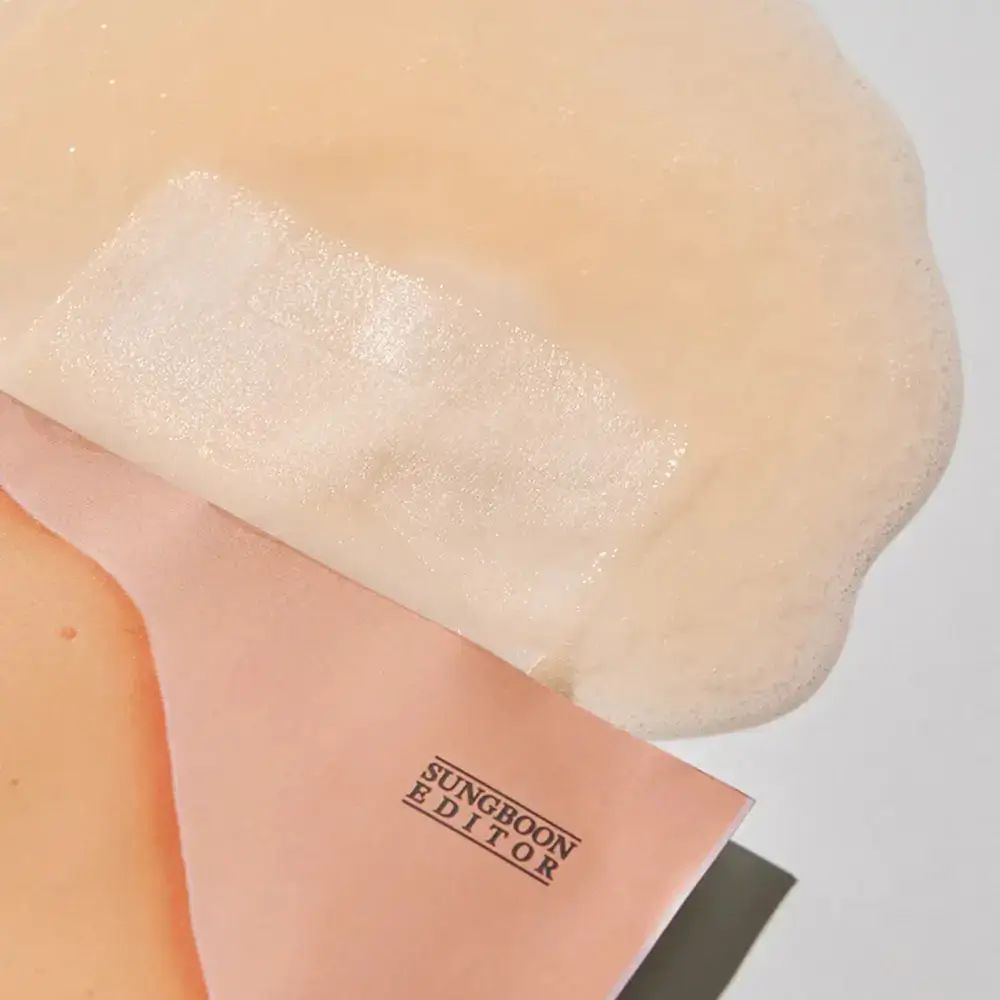 Gezichtsmasker gedeeltelijk uitgevouwen. Merk: SUNGBOON EDITOR. Roze verpakking.