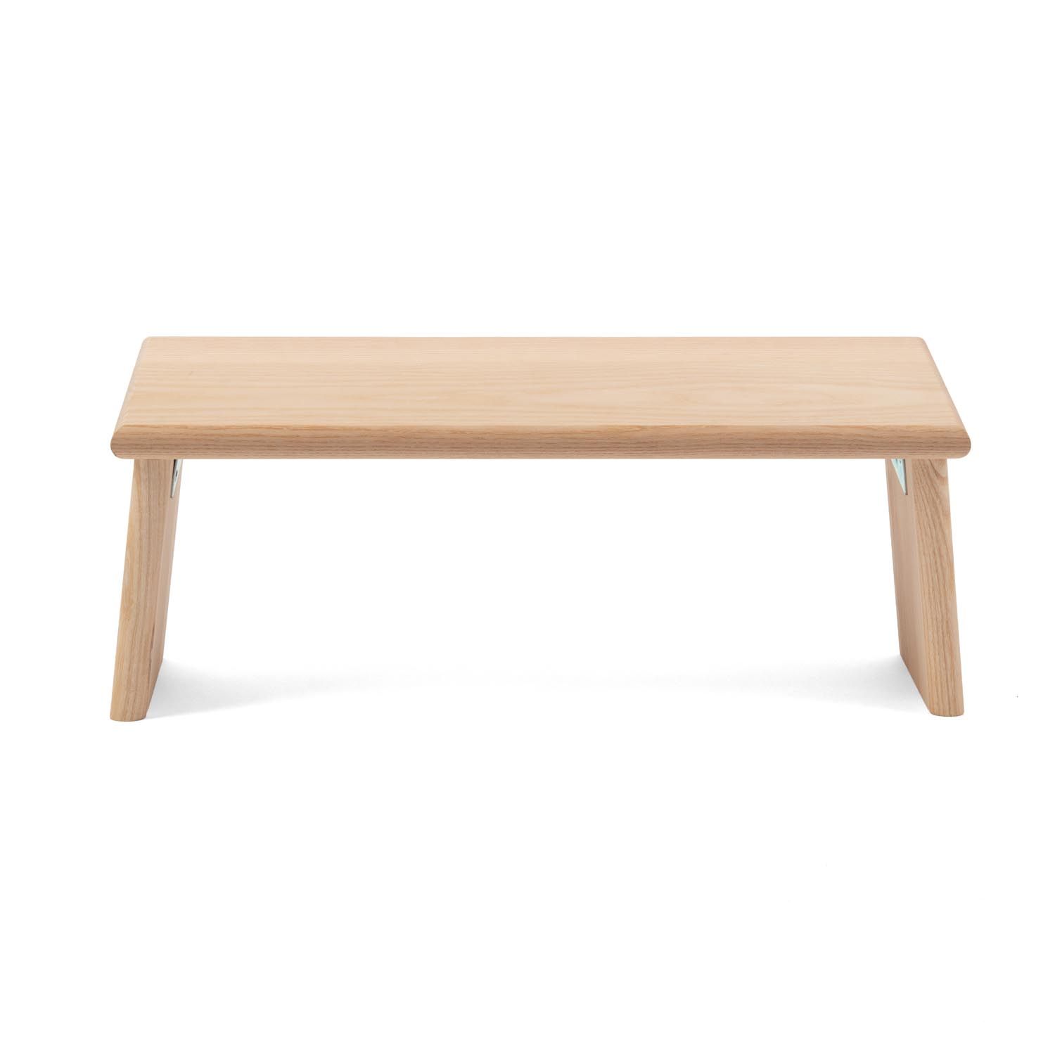 Meditatiebank van licht hout. Rechthoekig zitvlak, twee schuine poten. Metalen scharnieren.