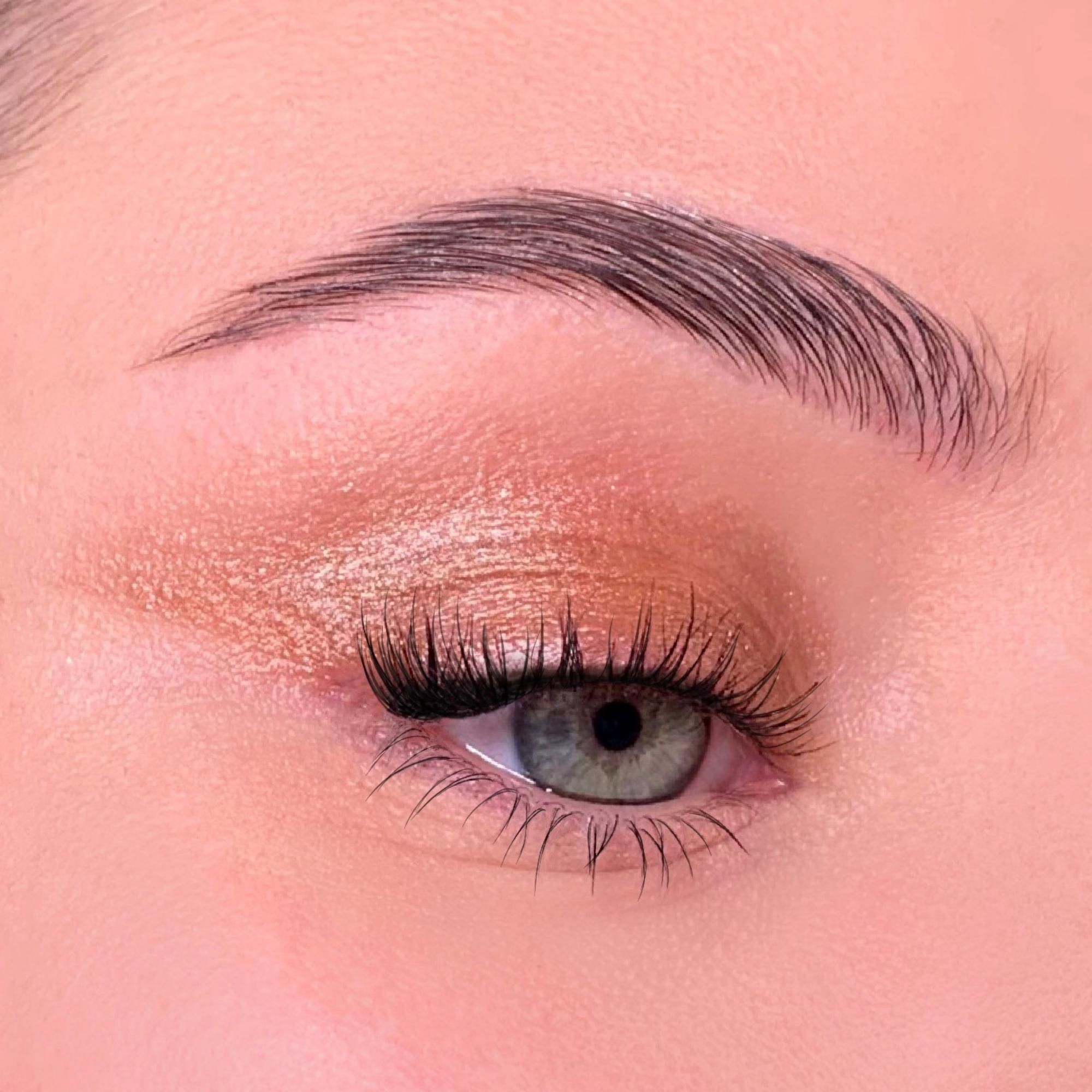 Close-up van een opgemaakt oog. Oogschaduw in goudtinten. Wenkbrauw en wimpers.