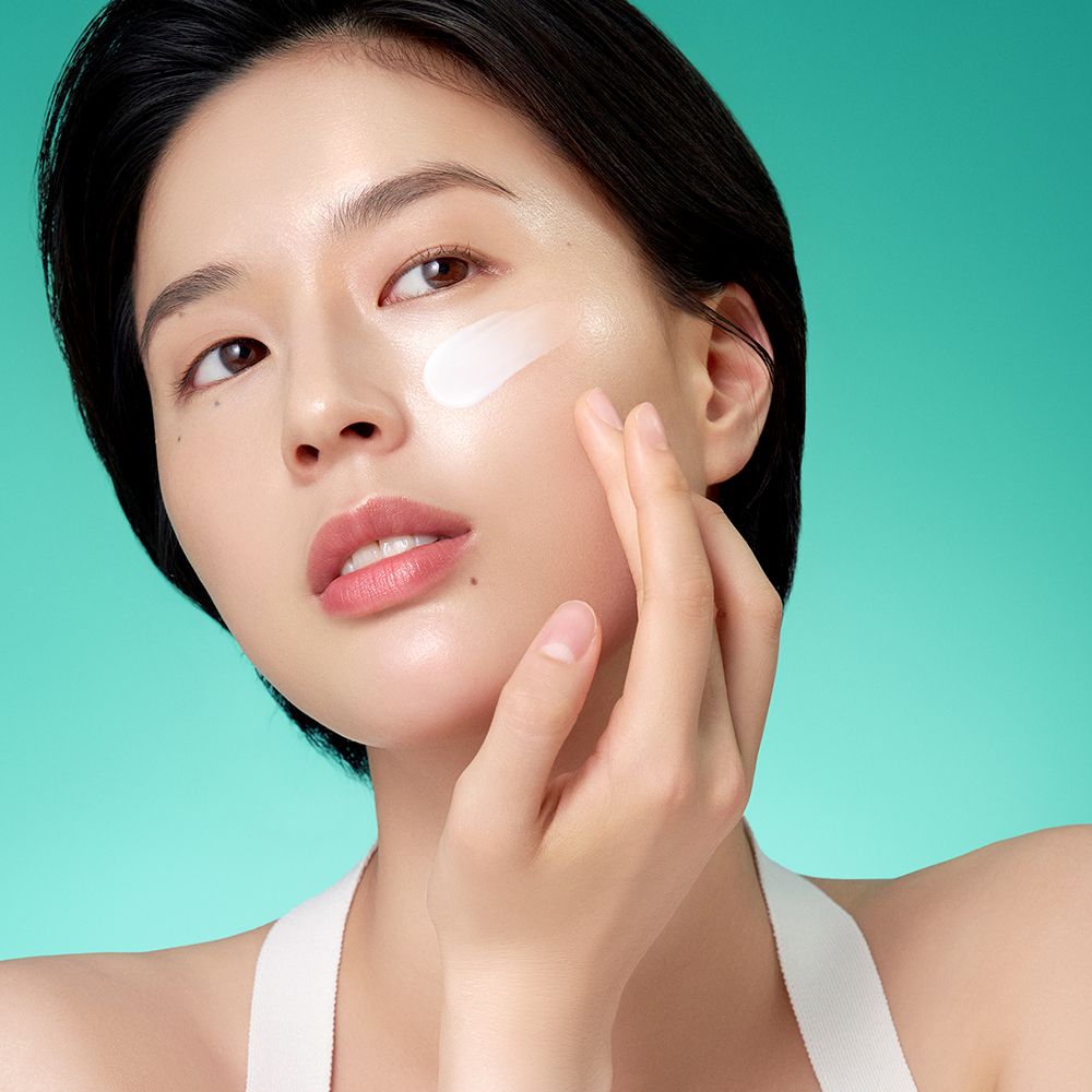 Une femme applique la crème Purito Mighty Bamboo Panthenol sur sa joue.