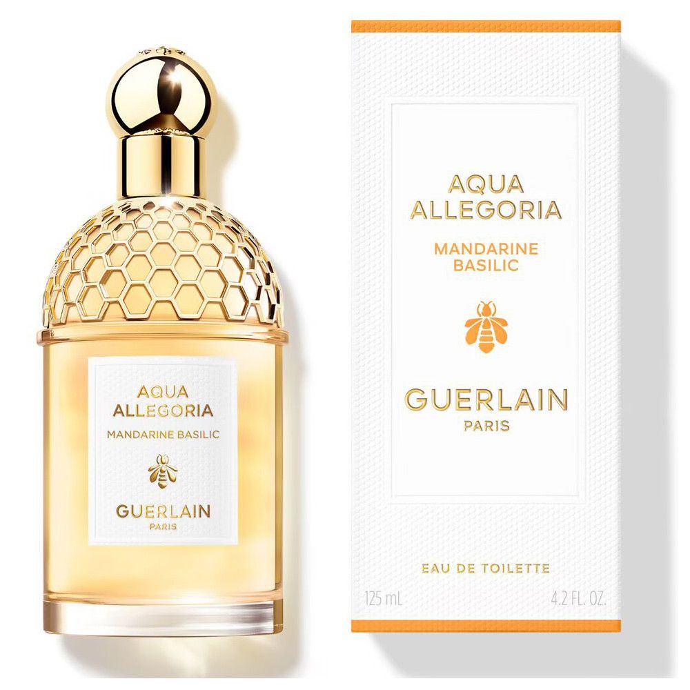 Gouden fles met honingraatpatroon en wit etiket. Witte doos met productnaam en logo.