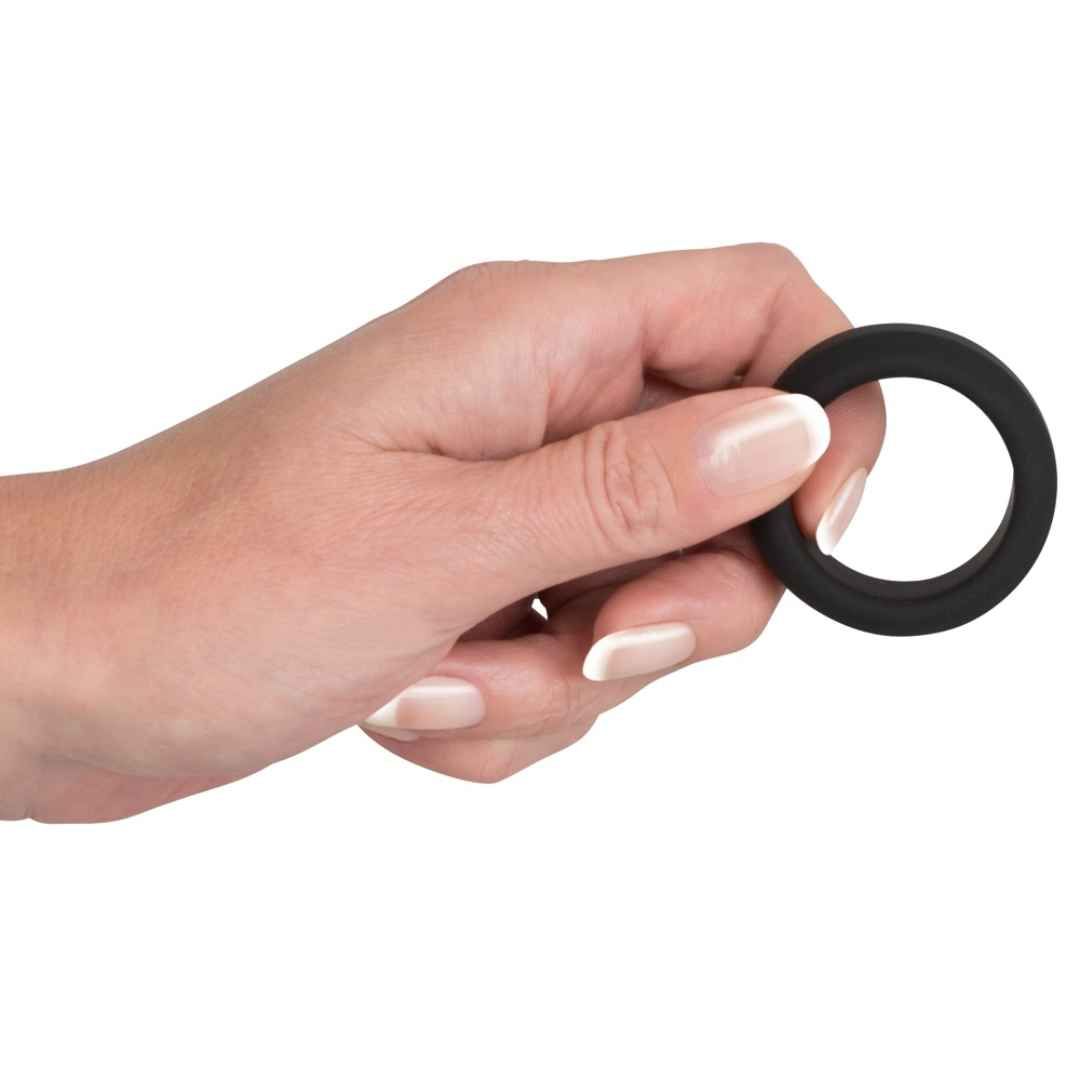 Main tenant une bague de pénis noire en silicone.