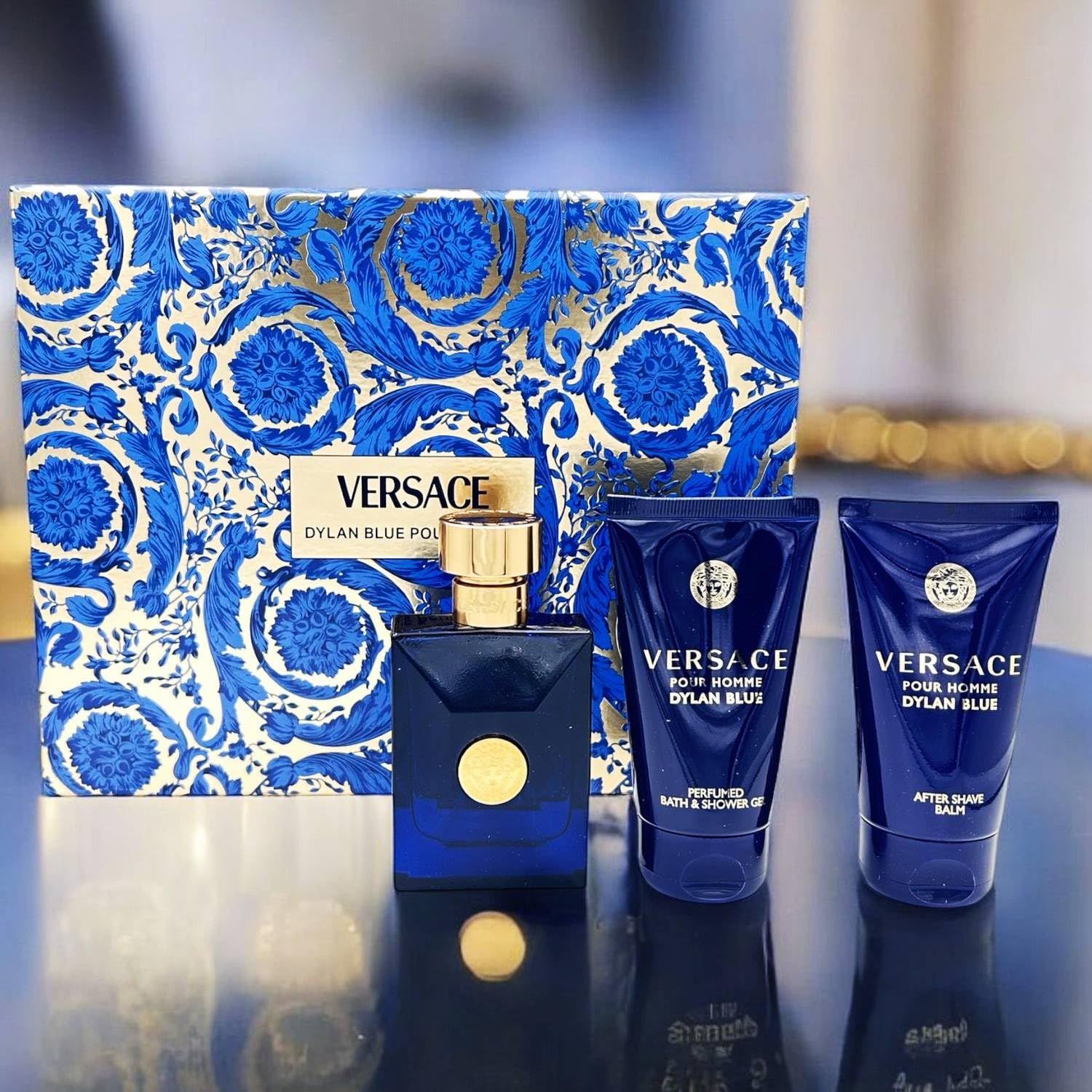 Coffret cadeau à motifs bleus, contenant une bouteille bleue et deux tubes bleus. Le logo Versace est visible.