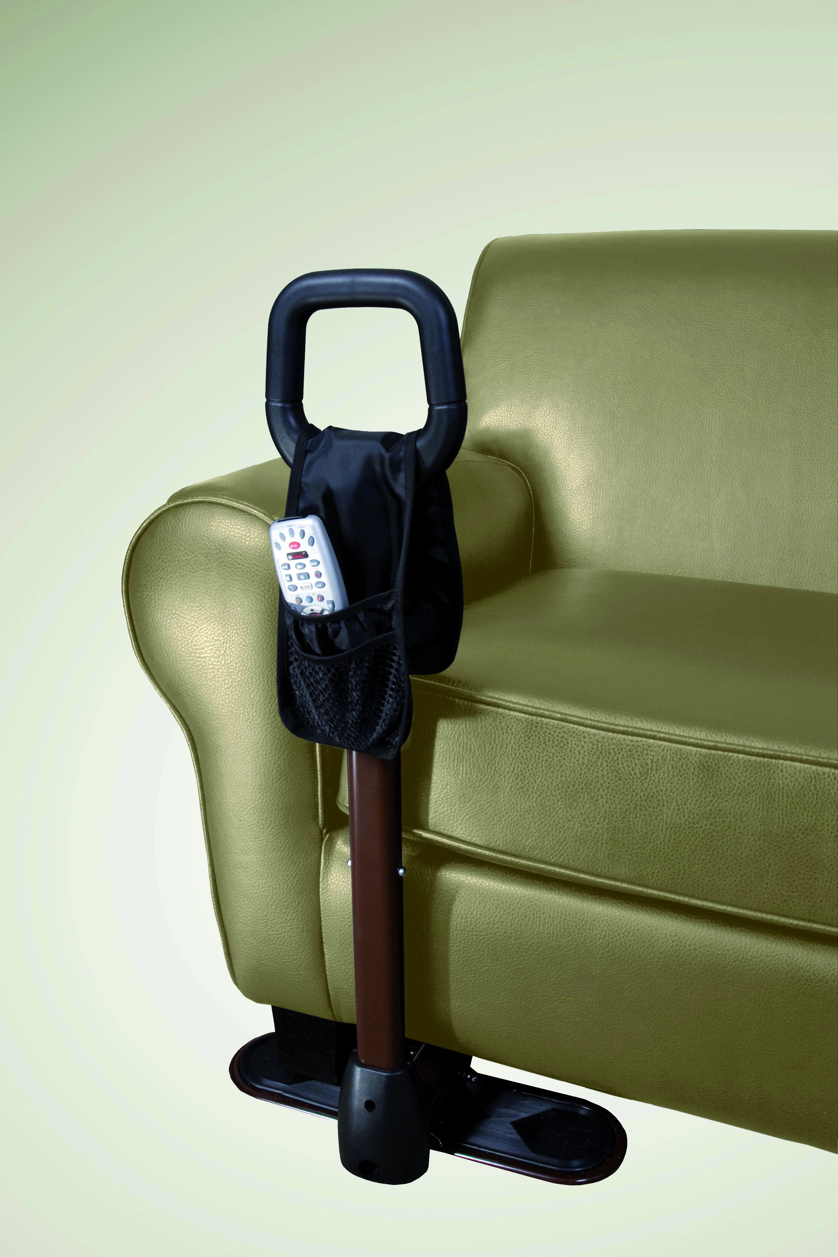 Aide au lever près d'un fauteuil vert. Poignée noire, tige marron, base noire. Avec poche et télécommande.