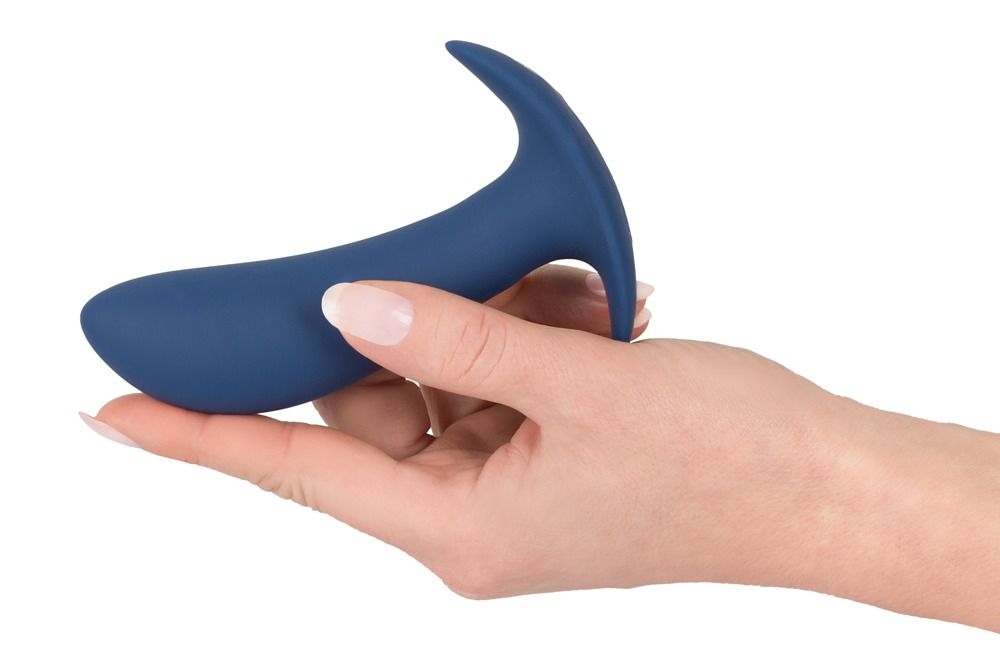 Hand die een donkerblauwe anale plug vasthoudt. Gebogen vorm, brede basis.