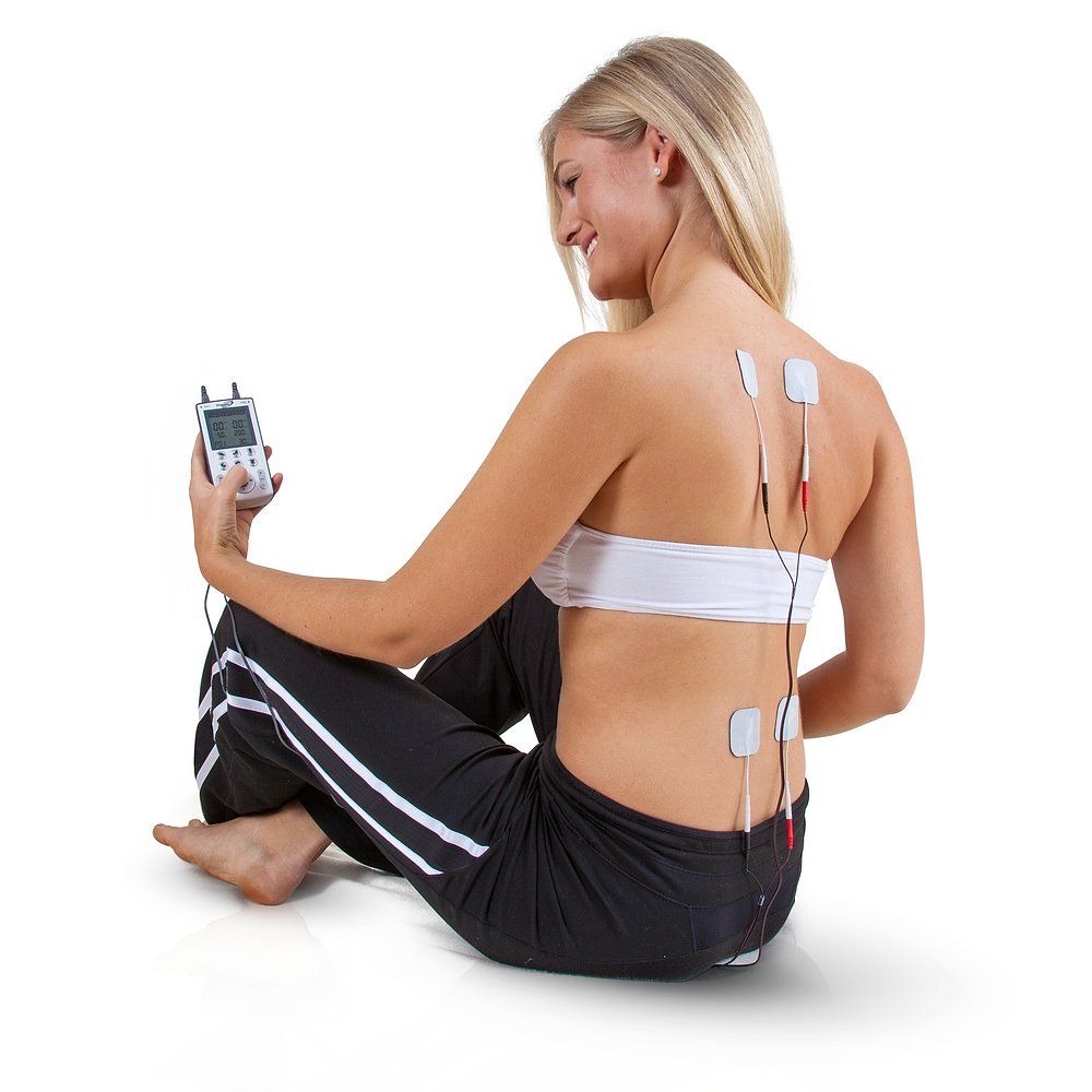 Femme assise, tenant un appareil TENS/EMS. Électrodes dans le dos. Appareil avec écran et boutons. Marque : Dittmann.