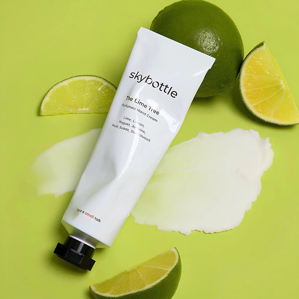 Tube blanc de crème pour les mains SKYBOTTLE "The Lime Tree" avec des citrons verts et de la crème sur fond vert. Texte: "The Lime Tree", "Perfumed Hand Cream".