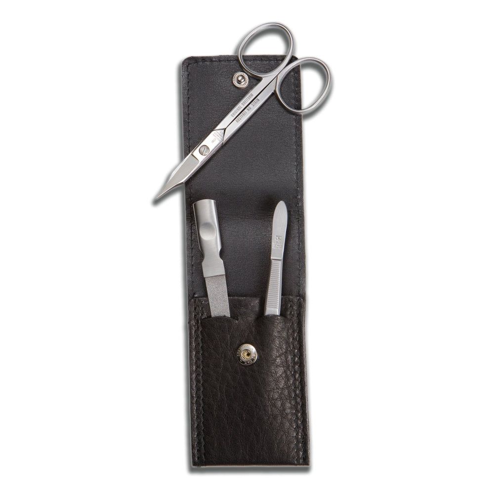 Étui de manucure avec ciseaux, lime à ongles et repousse-cuticules. Étui en cuir noir avec fermeture à bouton-pression. Outils en métal.