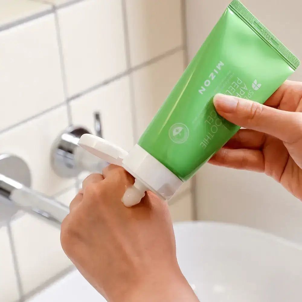 Groene tube wordt op hand gedrukt. Tekst: MIZON Apple Smoothie Peeling Gel. Product komt eruit.