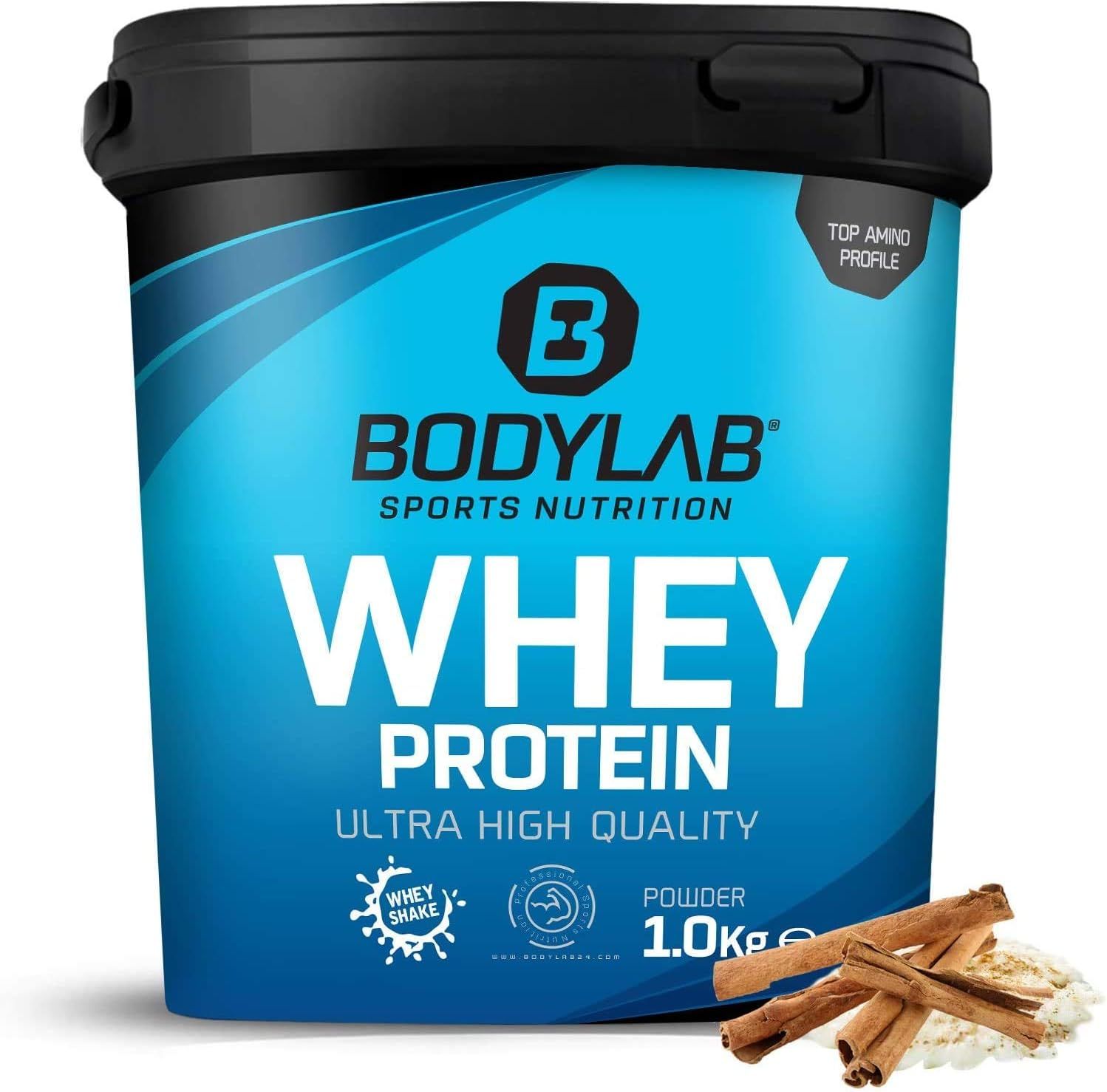 Pot bleu de protéine Bodylab Whey. Inscription: Whey Protein, Ultra High Quality, 1.0kg. Bâtons de cannelle et poudre à côté.