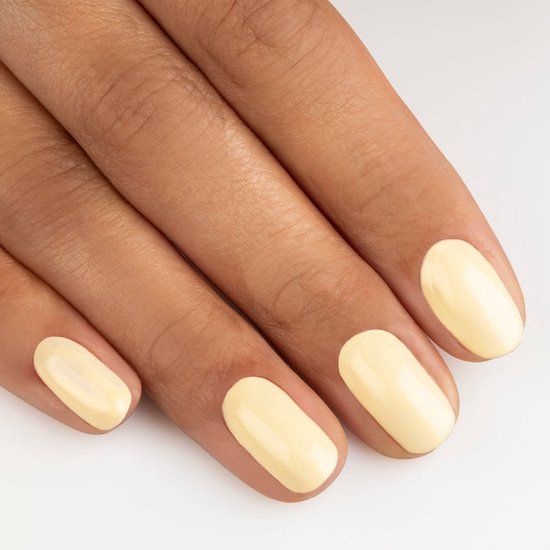 Main avec ongles vernis. Couleur : N32 Banana Cream. Finition brillante. Tous les ongles vernis.