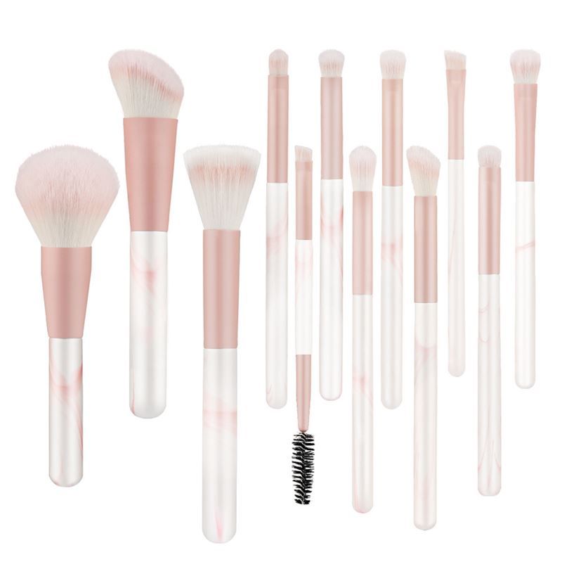 Ensemble de pinceaux de maquillage. Pinceaux avec manches roses et poils blancs. Différentes formes et tailles. Certains pinceaux ont des détails marbrés.