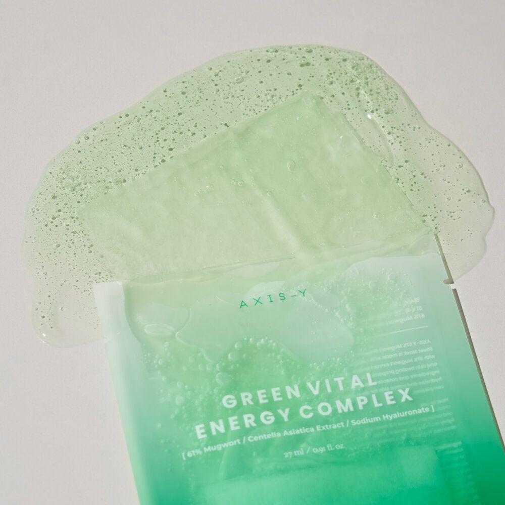 Open gezichtsmasker met vloeistof. AXIS-Y Green Vital Energy Complex. Groenachtige vloeistof en masker op witte achtergrond.