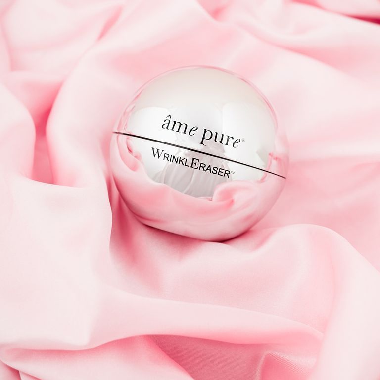 Un pot argenté fermé avec "âme pure WrinklEraser" sur soie rose.