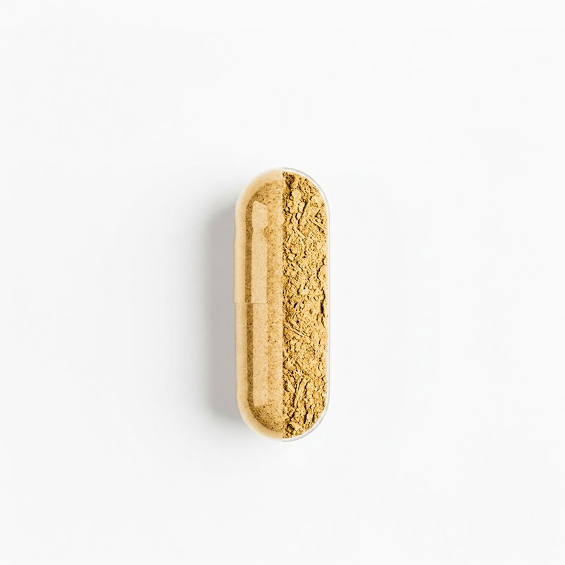 Une capsule unique remplie de poudre beige, sur fond blanc.