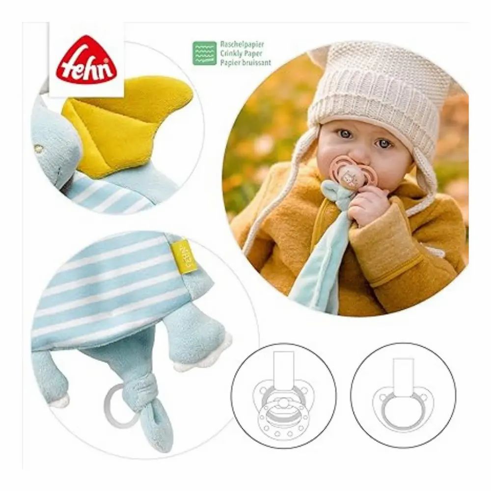 Baby met fopspeen en stoffen draak. Merk: Fehn. Op de draak: knisperpapier. Tekeningen van fopspenen.