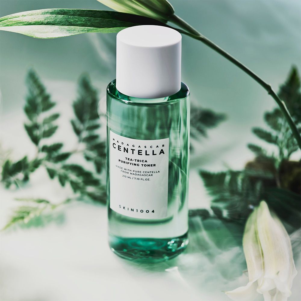 Bouteille de tonique vert entourée de feuilles et de fleurs.