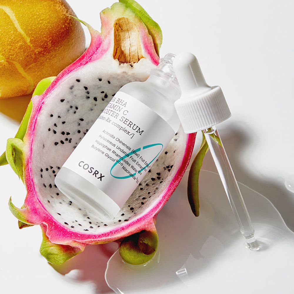 Flacon de sérum avec pipette, à côté d'un demi-fruit du dragon. Inscription : COSRX AHA BHA Vitamin C Booster Serum.