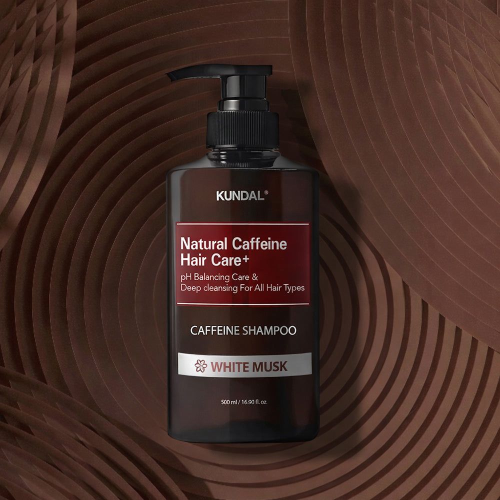 KUNDAL Natural Caffeine Hair Care+ Shampoo (White Musk) op een decoratieve bruine achtergrond.