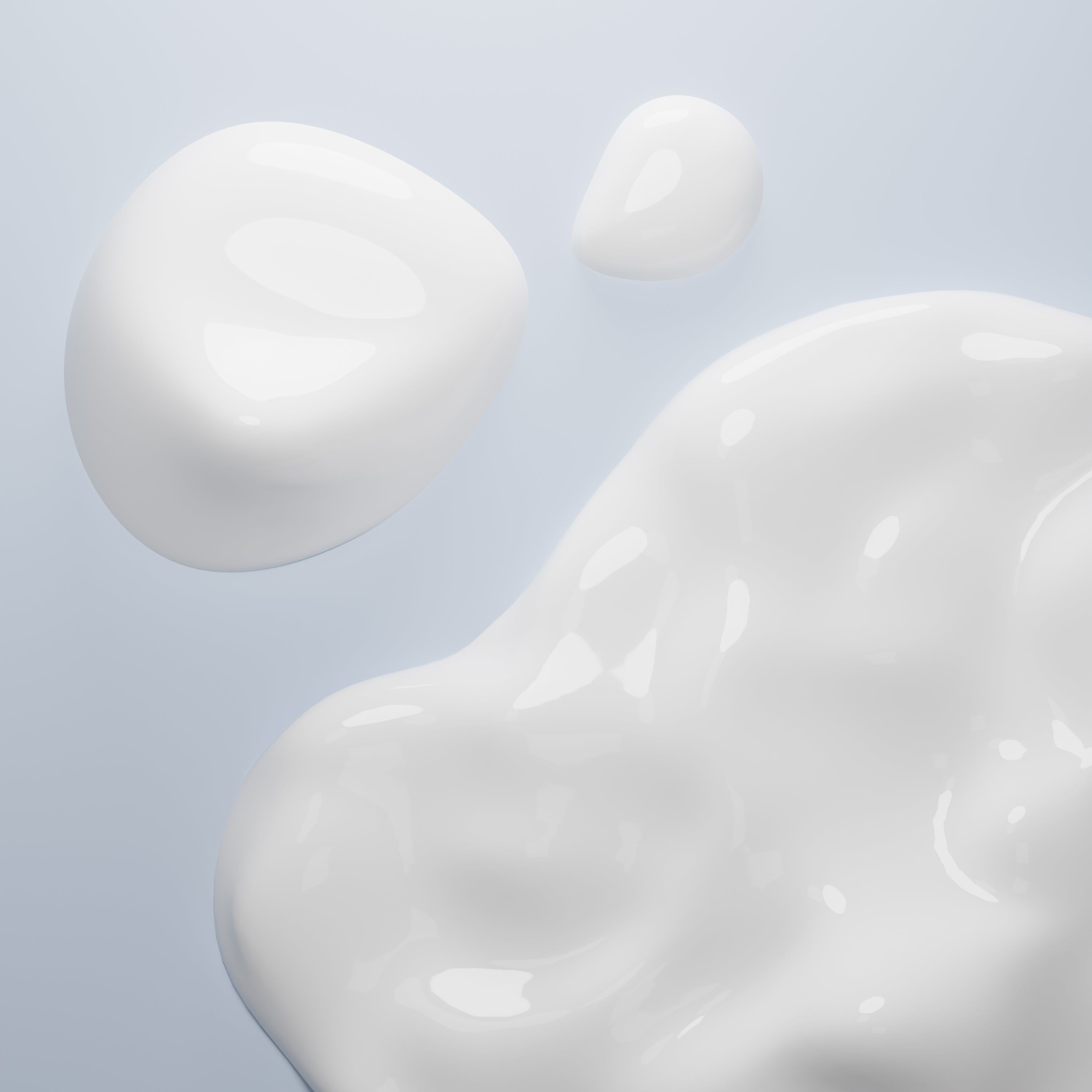 Gouttes de liquide blanc crémeux sur fond clair.