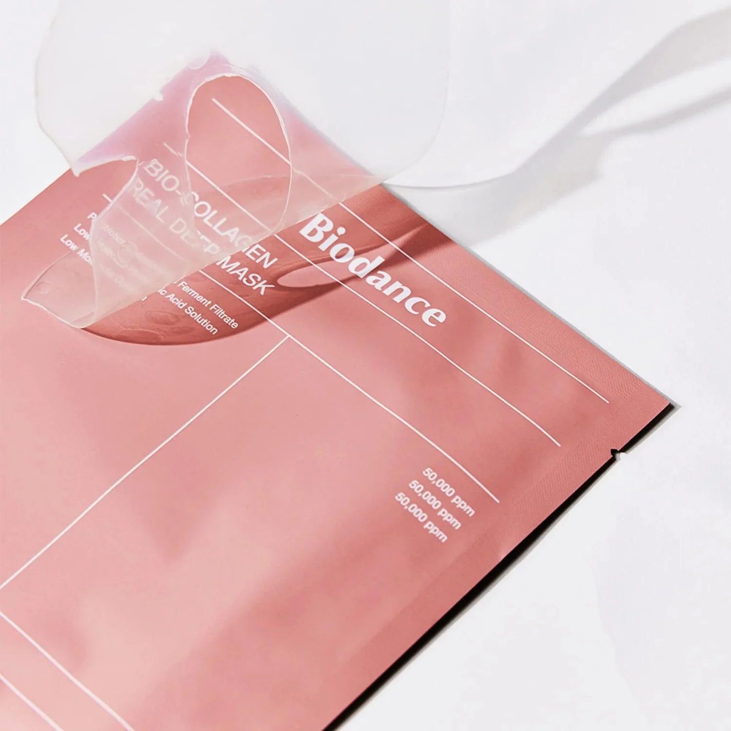 Emballage rose partiellement ouvert avec nom du produit. Texte : Bio Collagen - Real Deep Mask, 50 000 ppm.