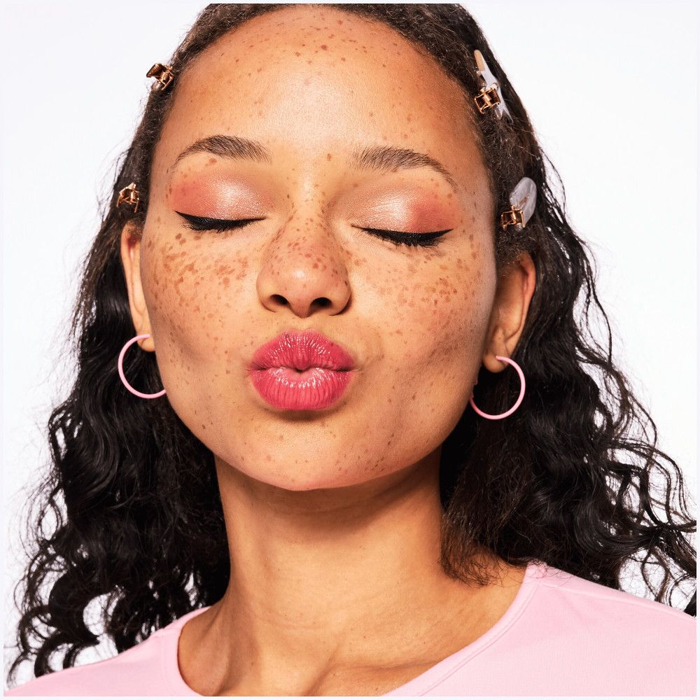 Une femme aux yeux fermés et aux lèvres maquillées. Elle fait une pose de moue.