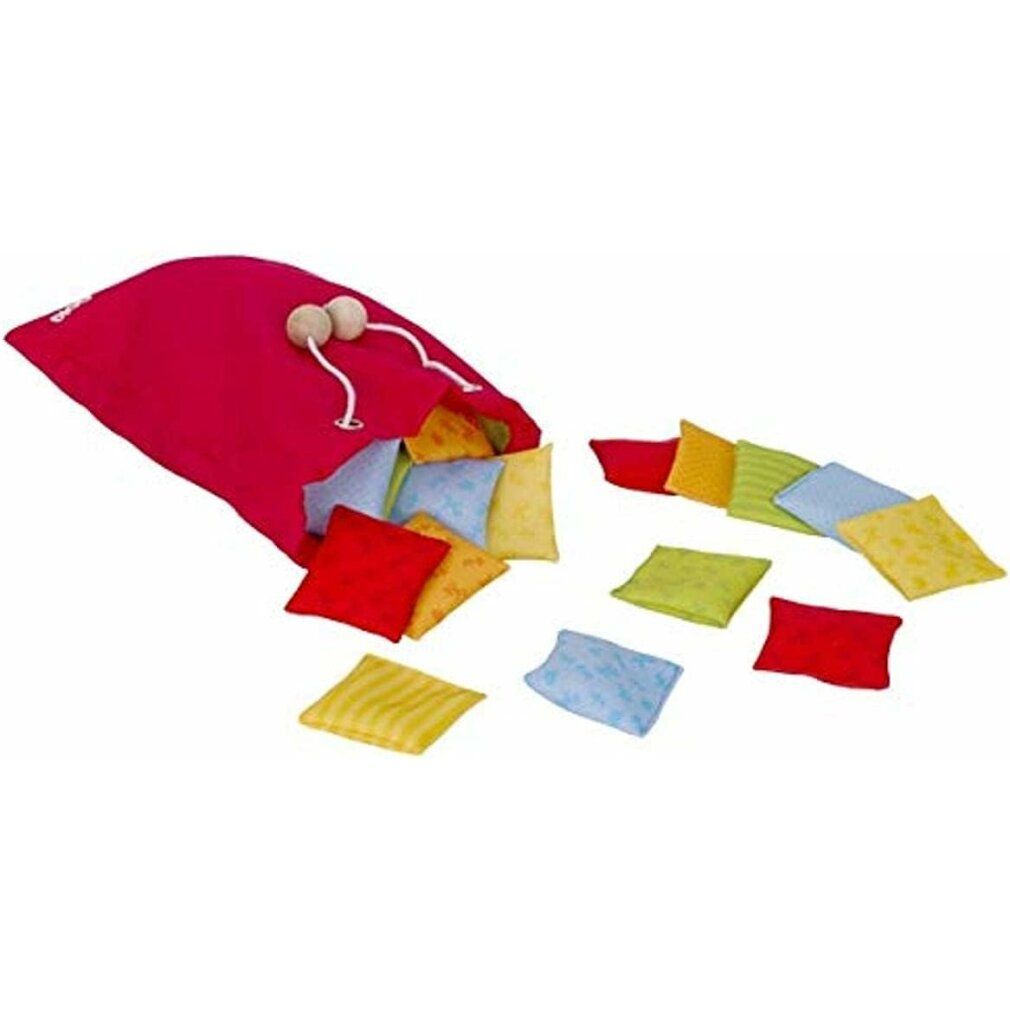 Sac rouge avec cordon contenant des coussins carrés colorés. Quelques coussins sont éparpillés.