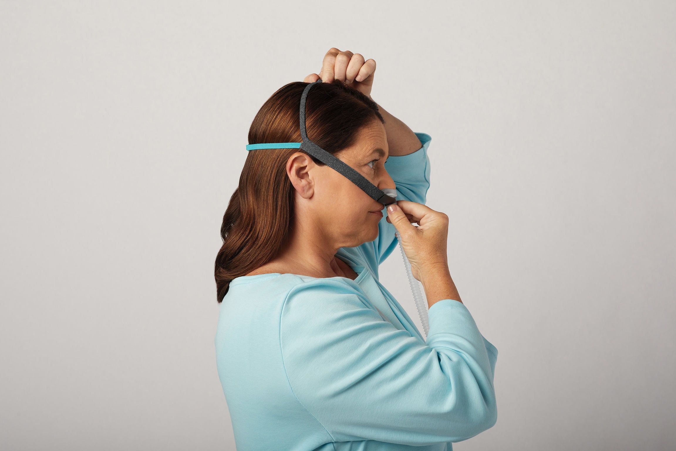 Vrouw zet CPAP-neusmasker met hoofdband op.