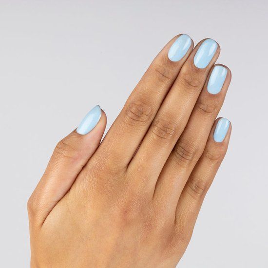 Main avec ongles peints en bleu clair. Cinq ongles à surface lisse. Couleur de peau claire.