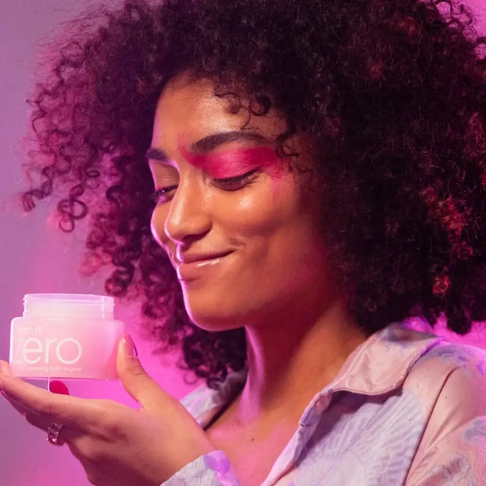 Persoon houdt roze pot met witte deksel vast. Woord "zero" zichtbaar.