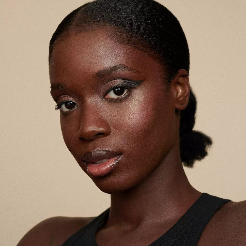 Portrait d'une femme à la peau foncée. Elle porte un trait de khôl noir sur l'œil.