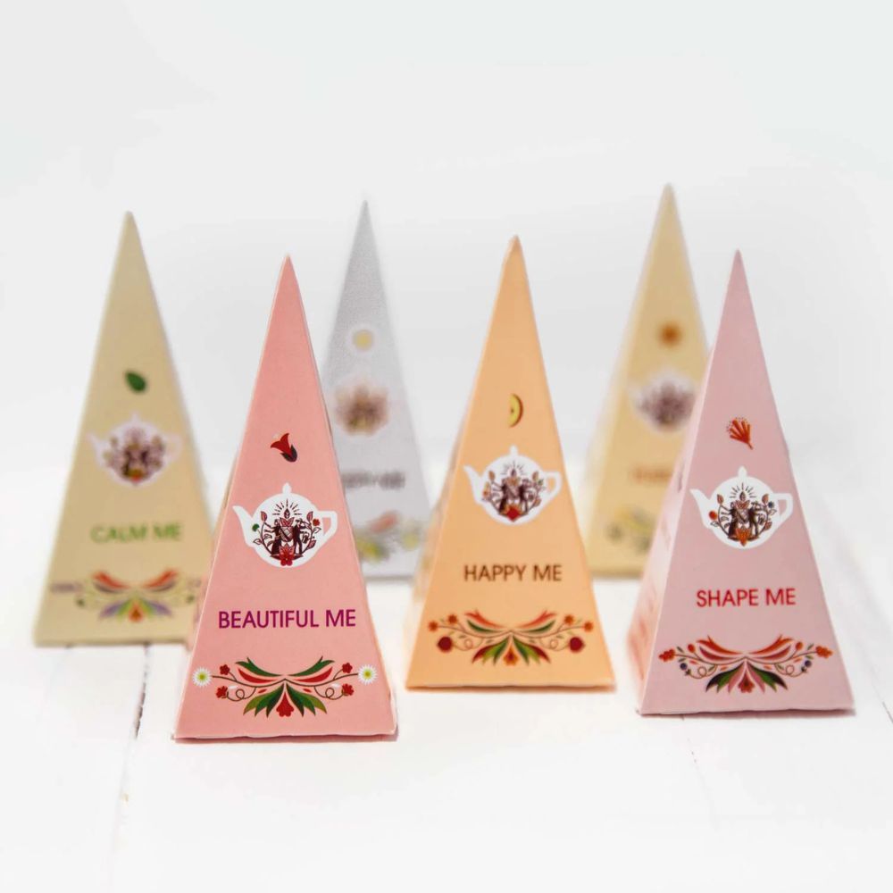 Zes piramidevormige theezakjes. Opschrift: Calm Me, Beautiful Me, Happy Me, Shape Me. English Tea Shop.