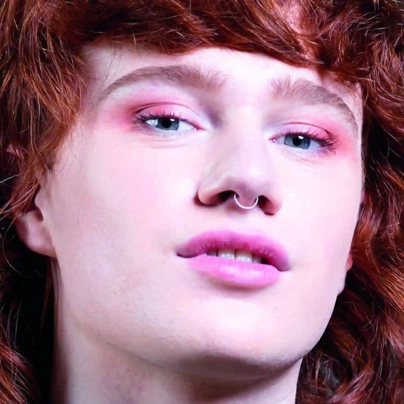 Close-up van een gezicht met roze oogschaduw en lippenstift.