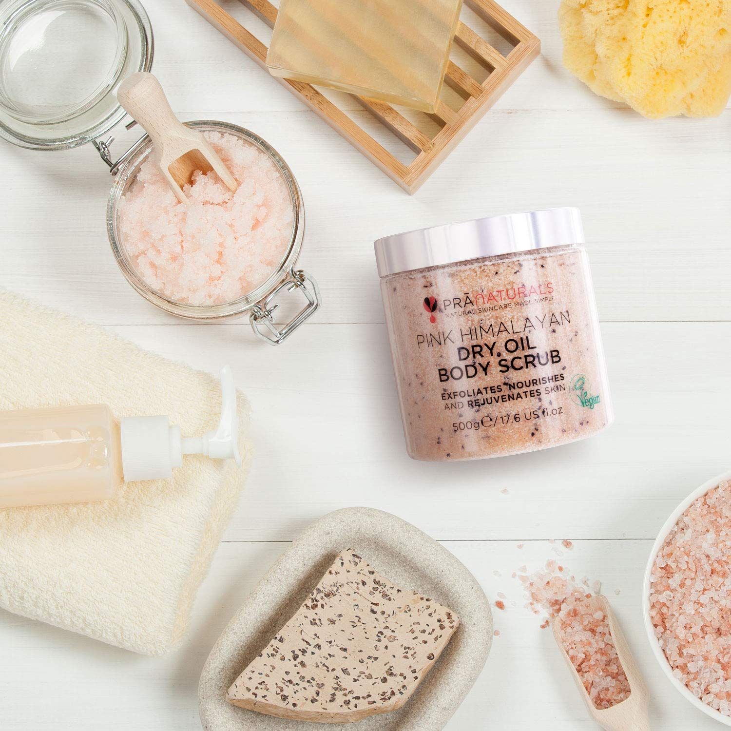 PraNaturals bodyscrub naast accessoires op witte ondergrond. Product in transparante pot. Andere producten en accessoires.