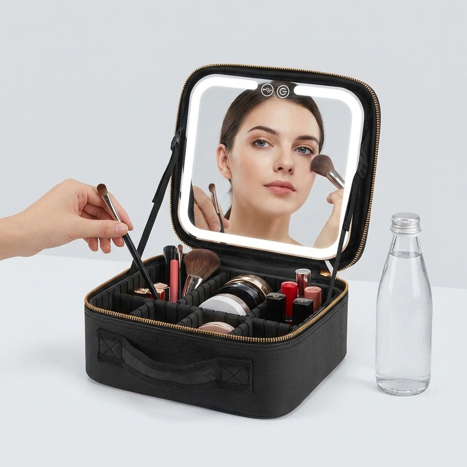 Trousse de maquillage noire avec miroir éclairé et compartiments.
