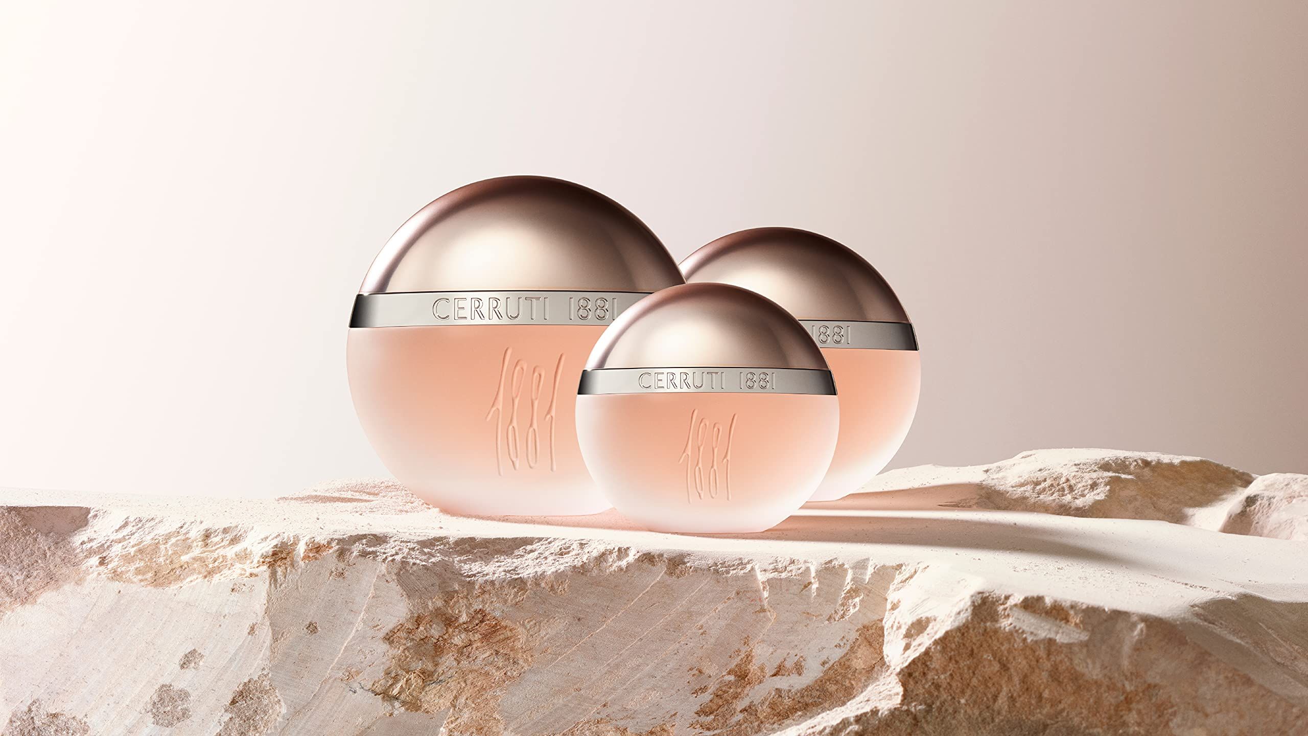 Trois flacons sur une surface. Flacons avec bouchons argentés et inscription Cerruti 1881. Liquide rose.