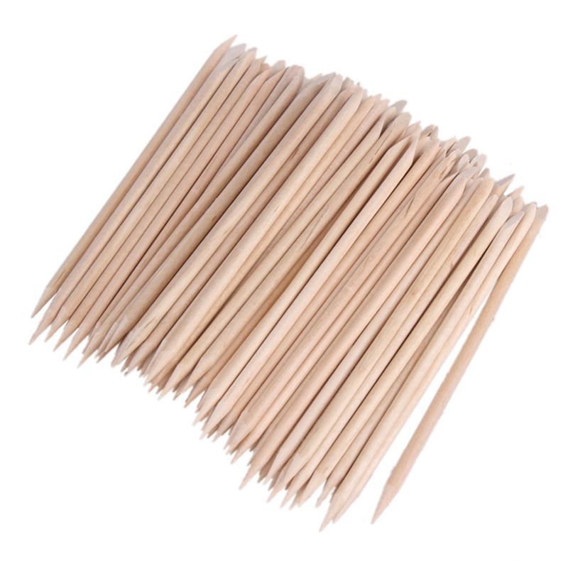 Tas de bâtonnets de manucure en bois de rose. Couleur bois, pointes pointues et arrondies. De nombreux bâtonnets sont regroupés.