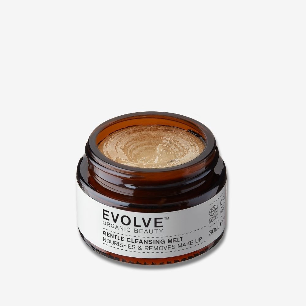 Pot en verre brun contenant un produit doré. L'étiquette indique "Evolve Organic Beauty Gentle Cleansing Melt".