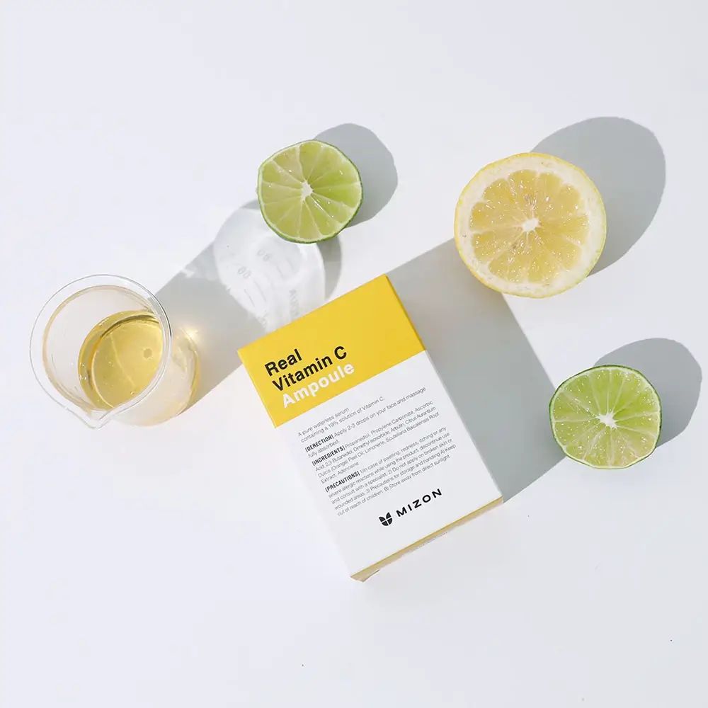 Verpakking met geel etiket en opschrift: Real Vitamin C Ampoule. Citroenen, limoenen en een beker ernaast.