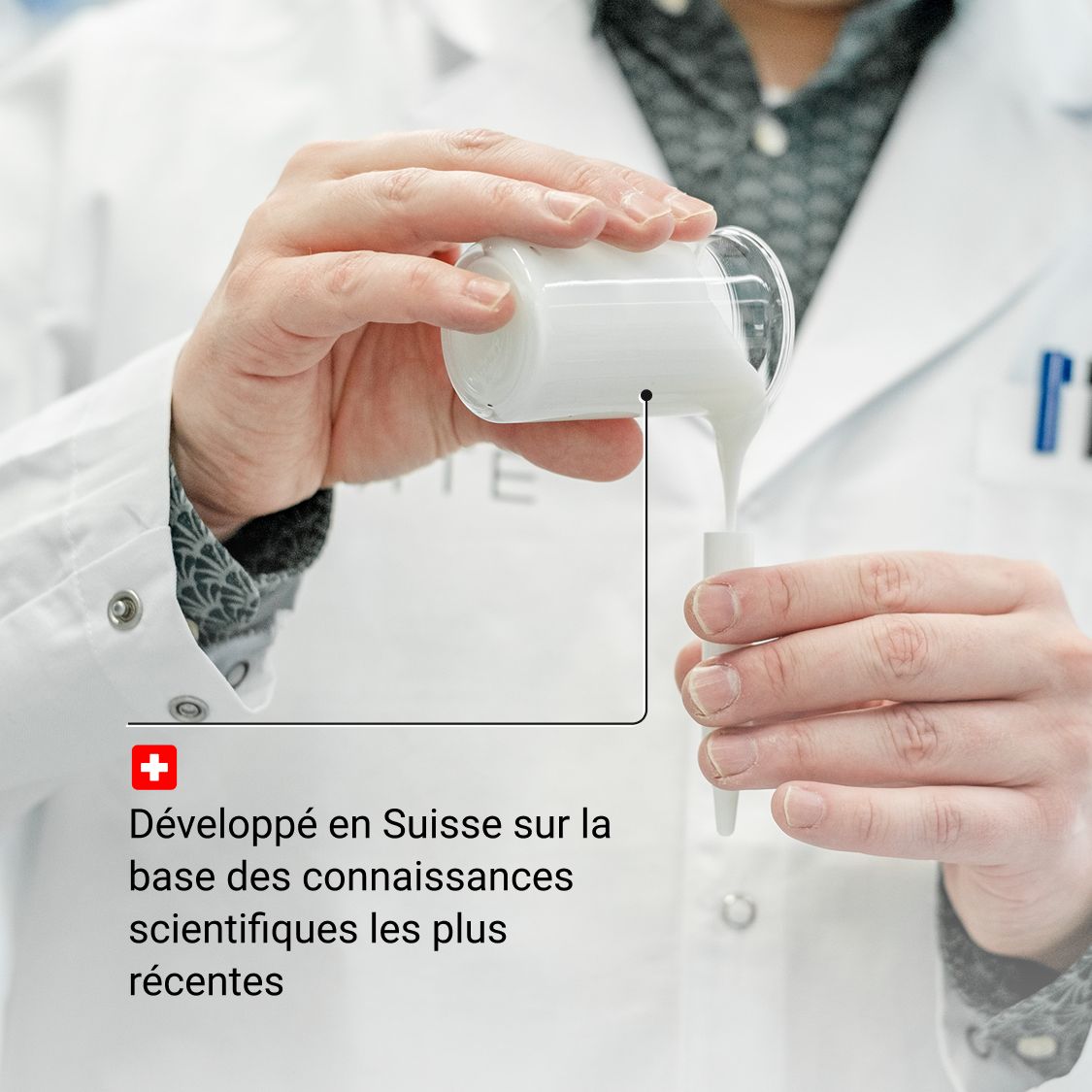 Mains versant du sérum d'un récipient en verre dans un applicateur. Texte: Développé en Suisse sur la base des connaissances scientifiques.