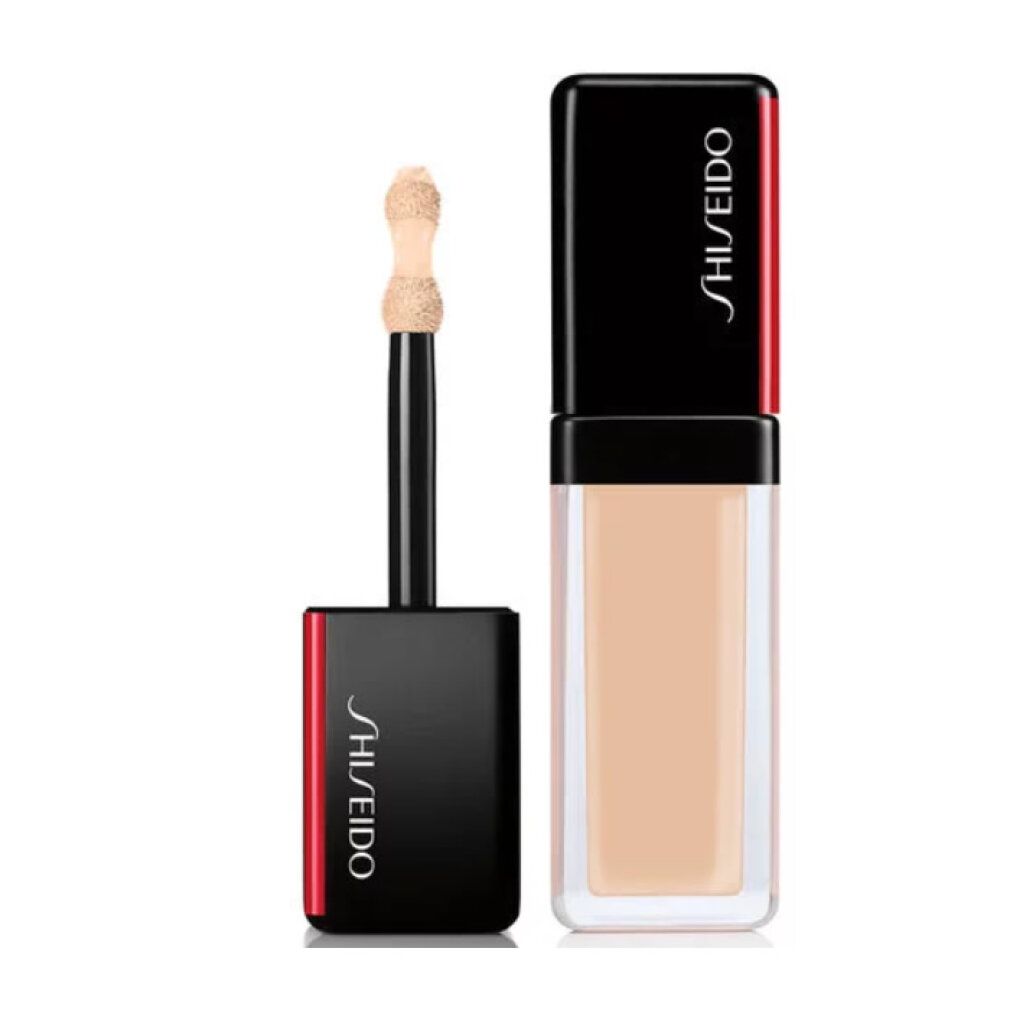 Flacon de correcteur avec applicateur. Capuchon noir avec accent rouge. Inscription Shiseido. Texture beige clair.